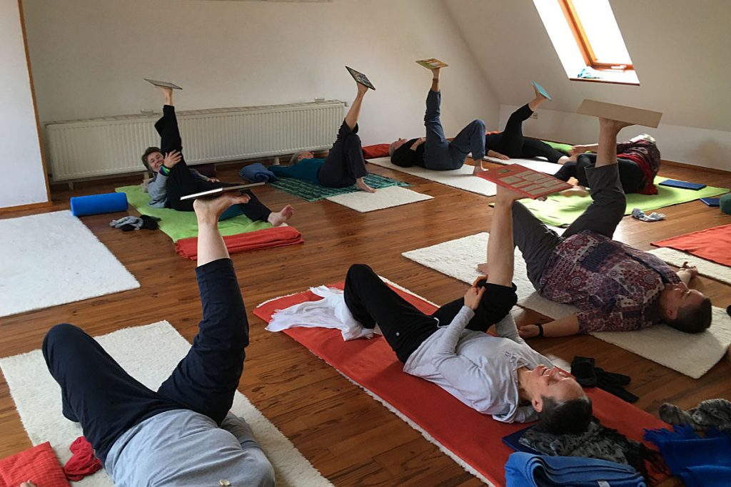 Mehrere Personen liegen auf dem Boden und halten ein Bein in die Luft