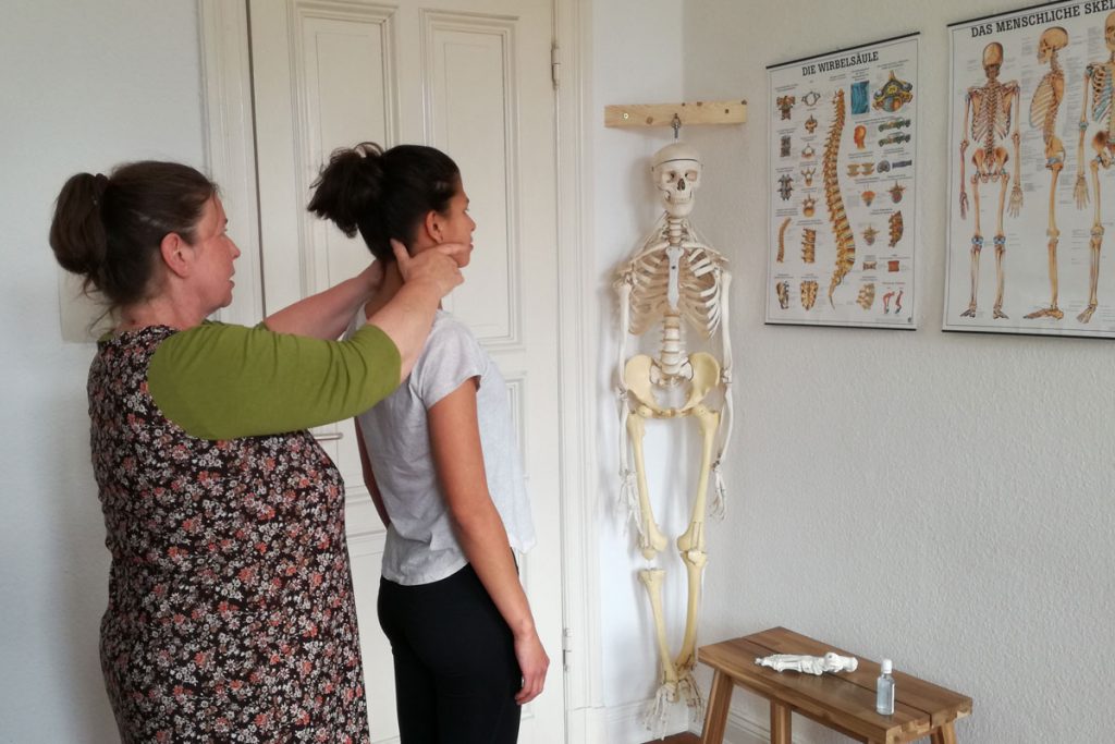 Luka Skywalkerin steht hinter einer Patientin und richtet ihre Halswirbel