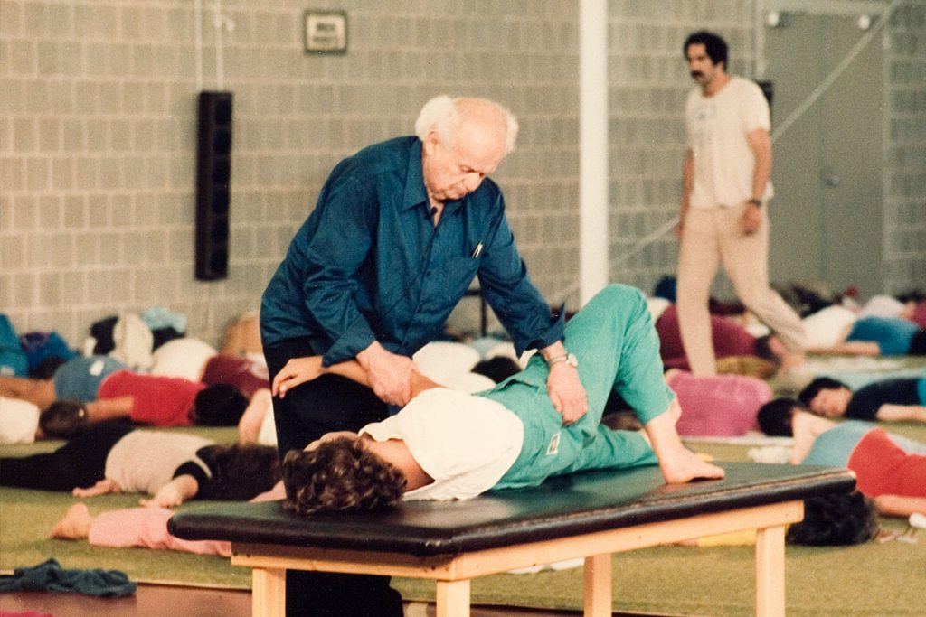 Moshe Feldenkrais praktiziert seine Methode an einer liegenden Person